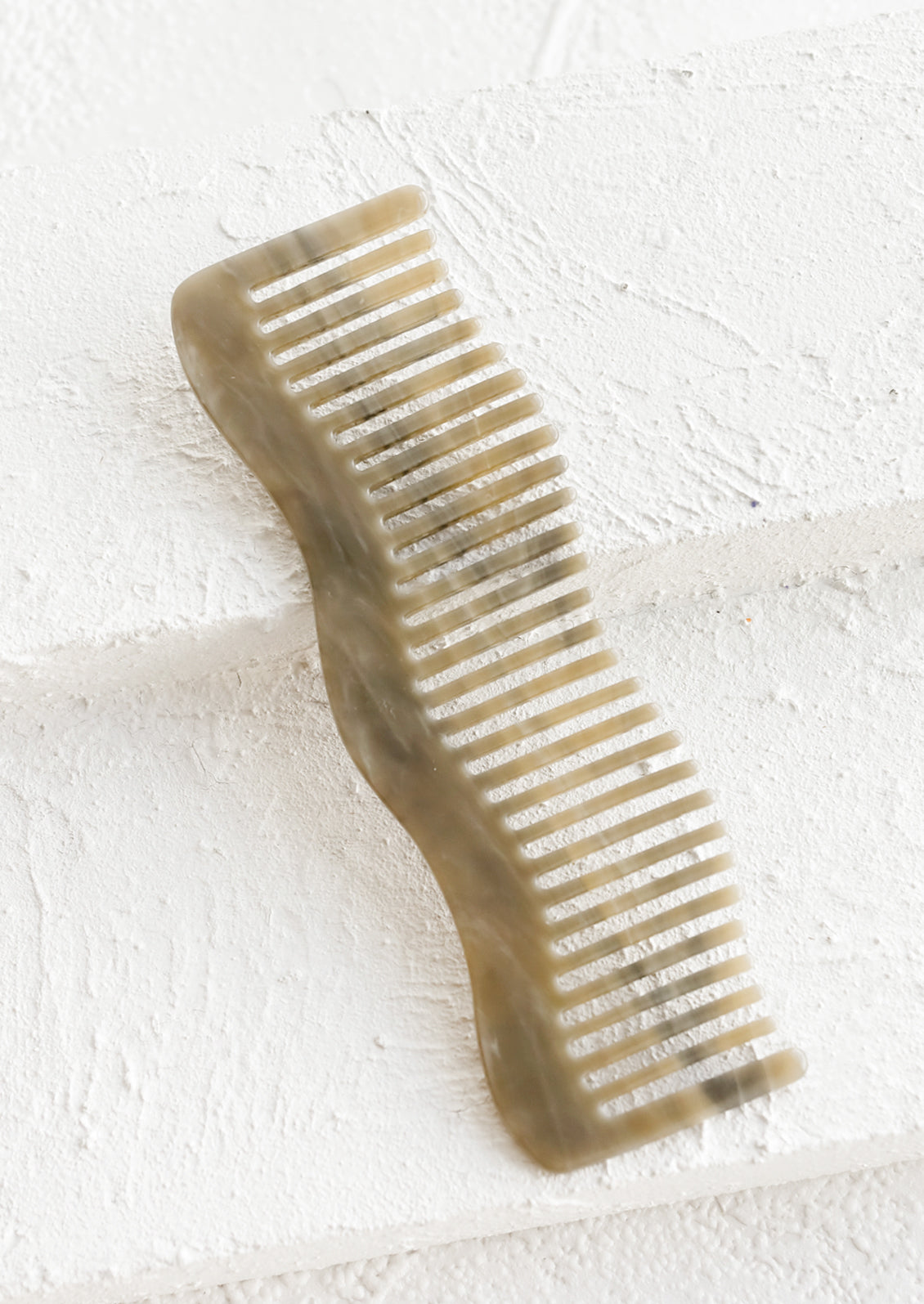 A wavy shaped acetate comb in stone grey.