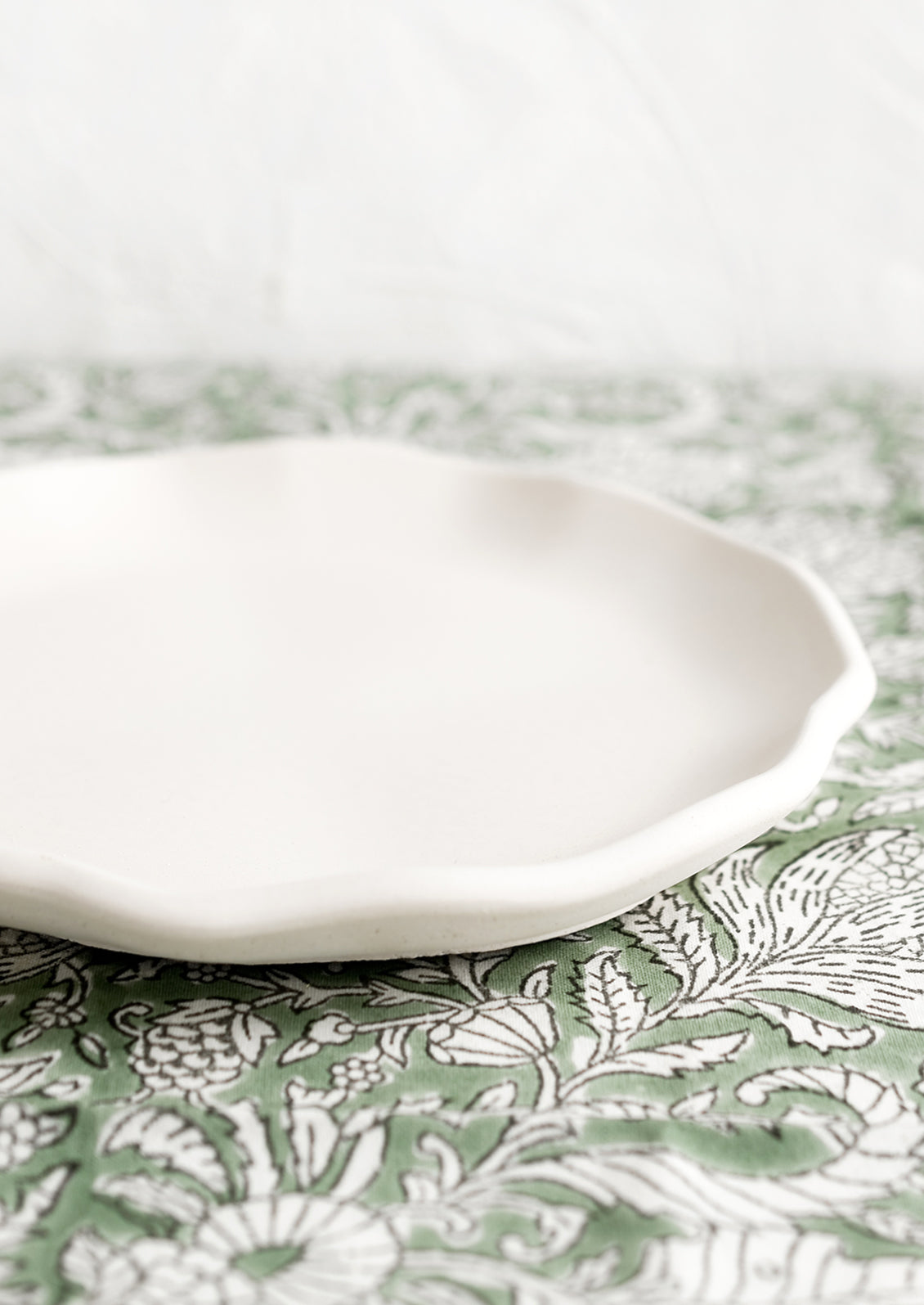 A round white concrete tray with ruffled, wavy edges.