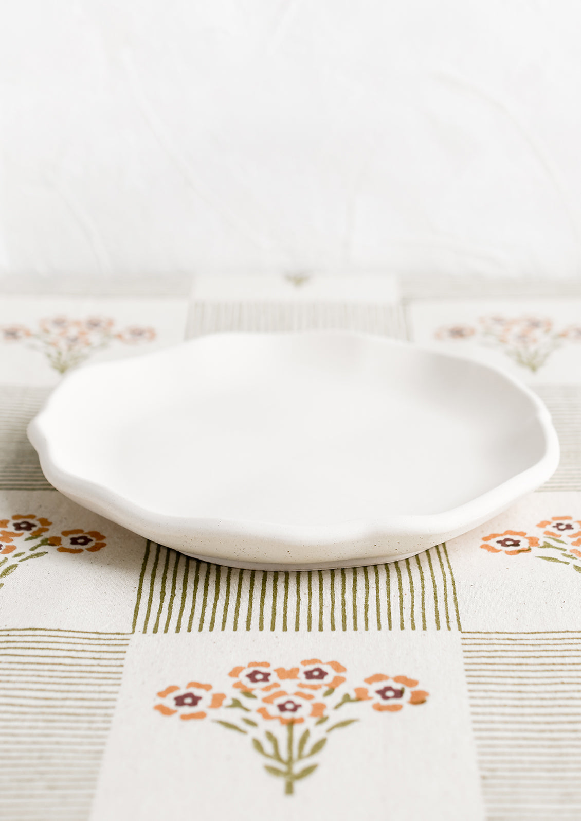 A round cream concrete tray with ruffled, wavy edges.