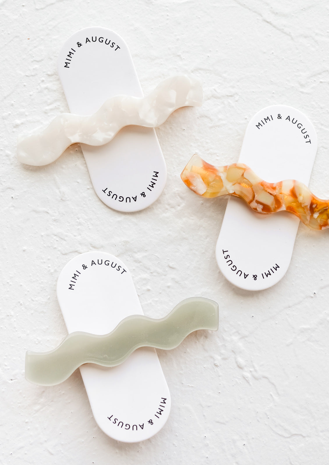 Three hair clips with wavy squiggle design in assorted colors.