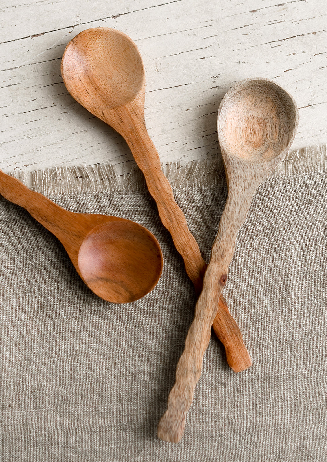 Three wooden spoons with wavy handles in various wood tones.
