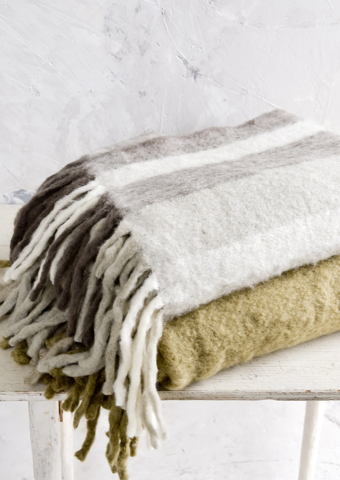 Two fuzzy throw blankets, stacked on a table.