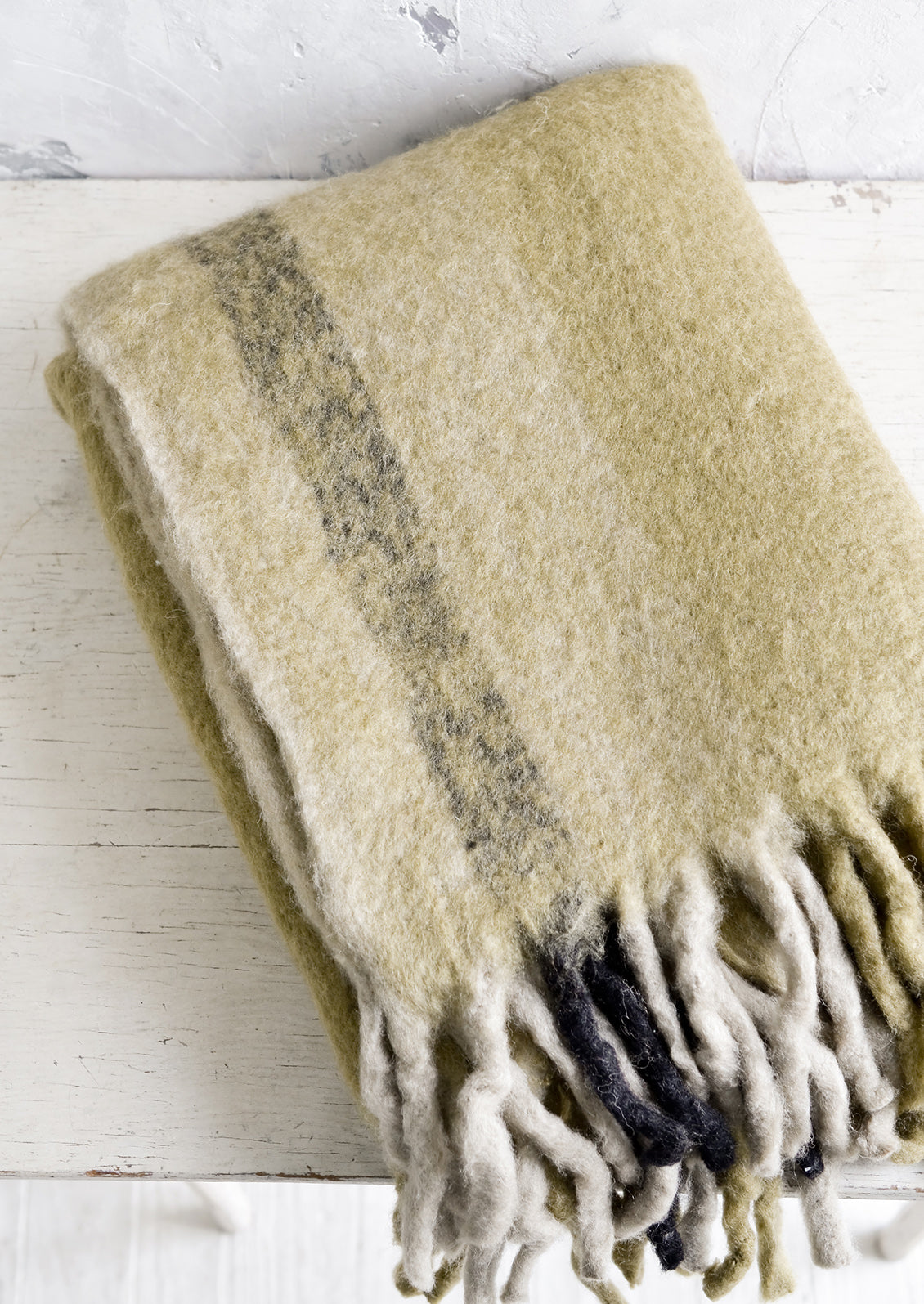 A fuzzy throw blanket with exaggerated fringe in ochre multi.