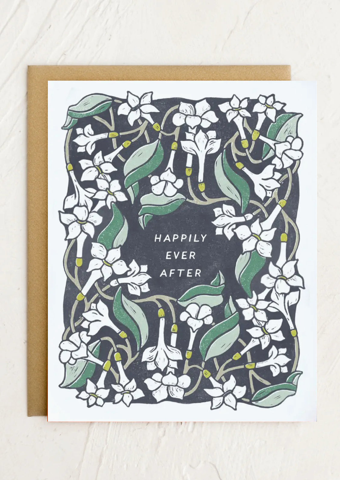 A white floral print greeting card reading "Happily Ever After" at center.