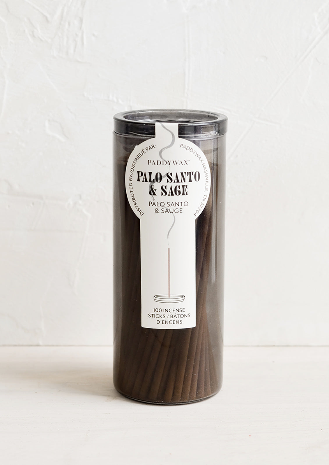 A grey glass jar with incense sticks in palo santo scent.
