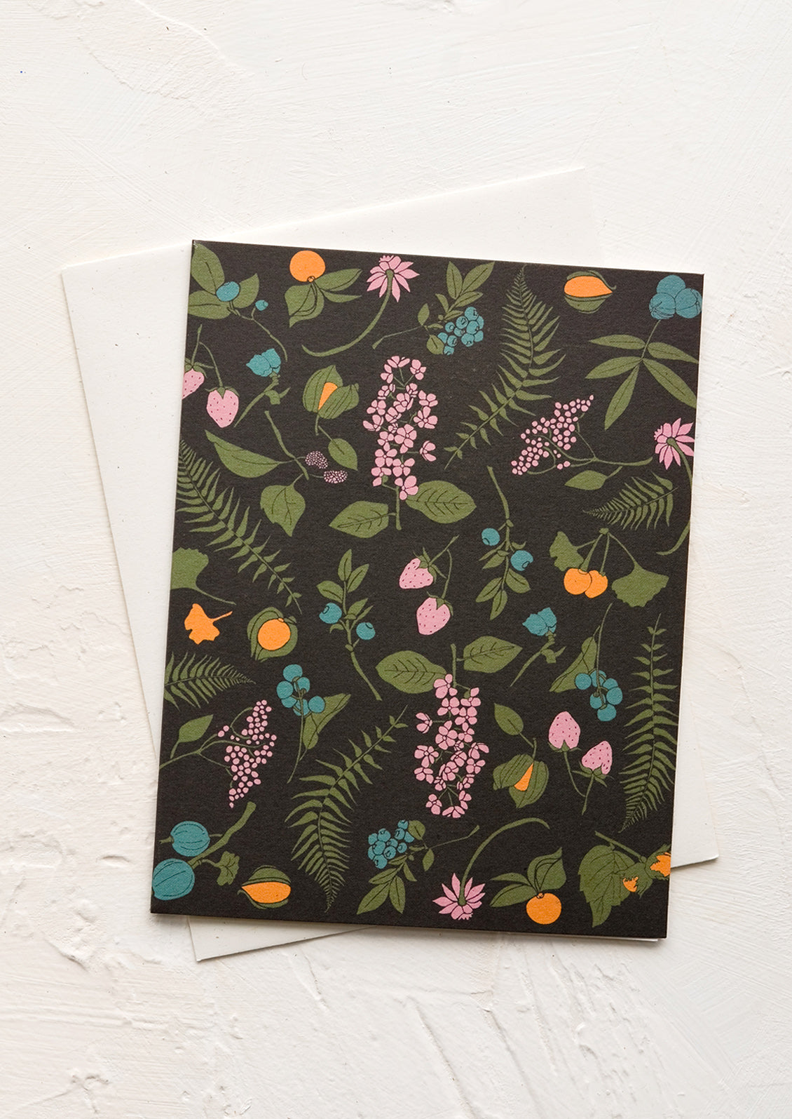 A greeting card with black background and berry/fern print.
