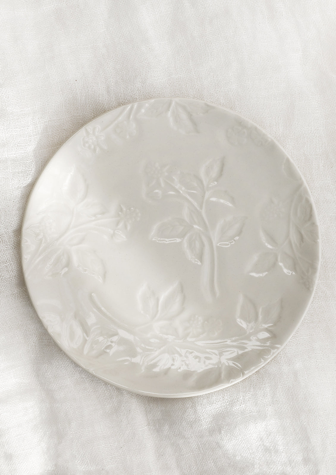 A round ceramic dessert plate in ivory with tonal raspberry pattern.