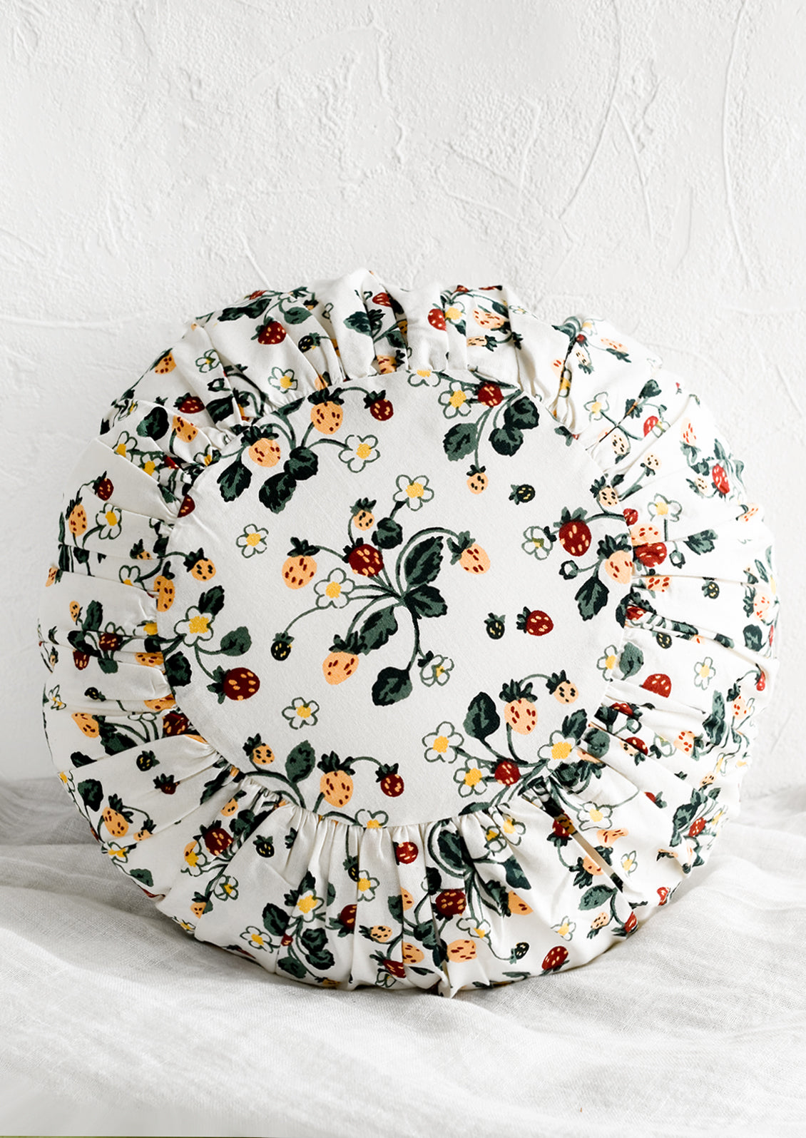 A round cushion with pleated detailing in strawberry print.