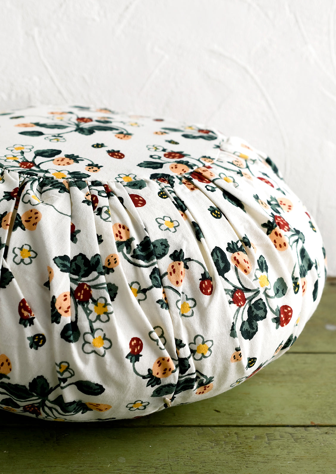 A round cushion with pleated detailing in strawberry print.