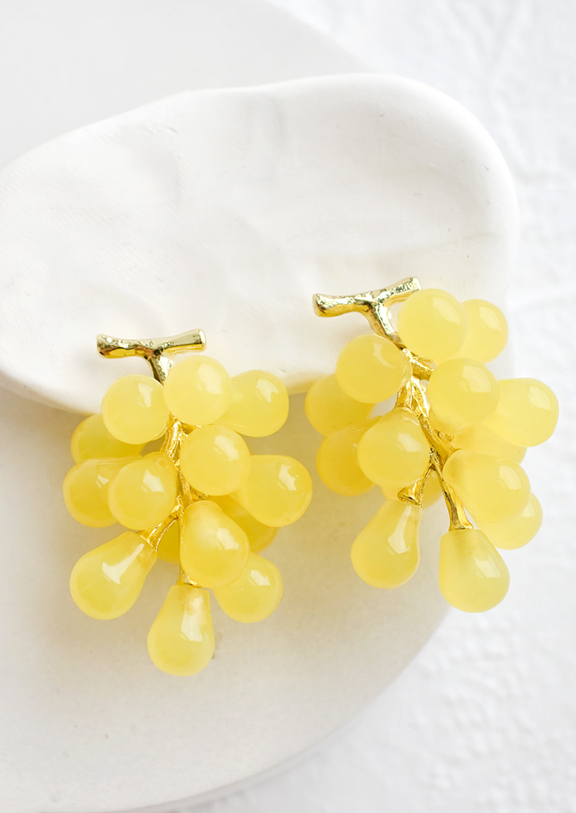 A pair of earrings in the shape of green grape bunches.