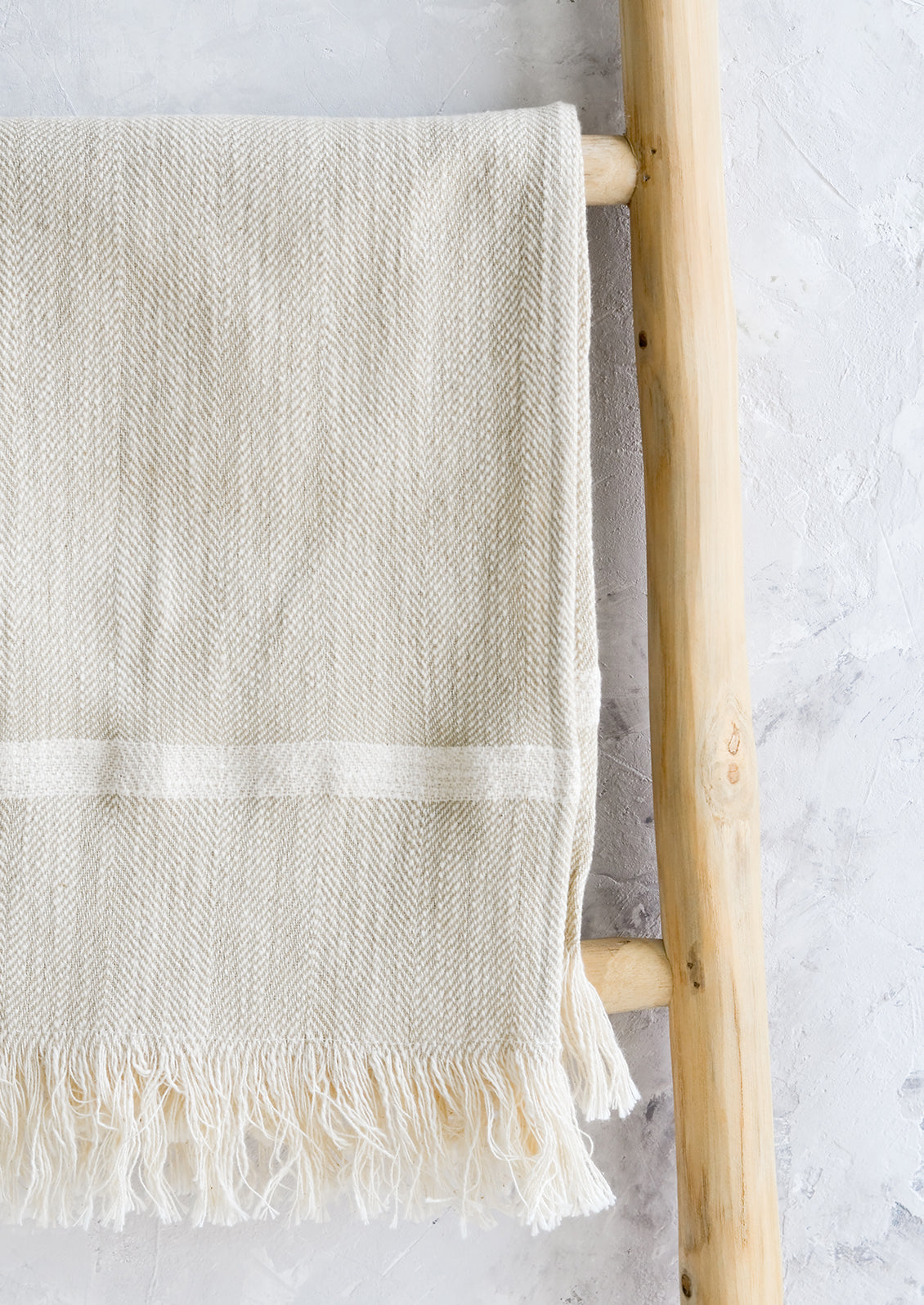 A woven kitchen towel with white stripe hanging on a ladder.