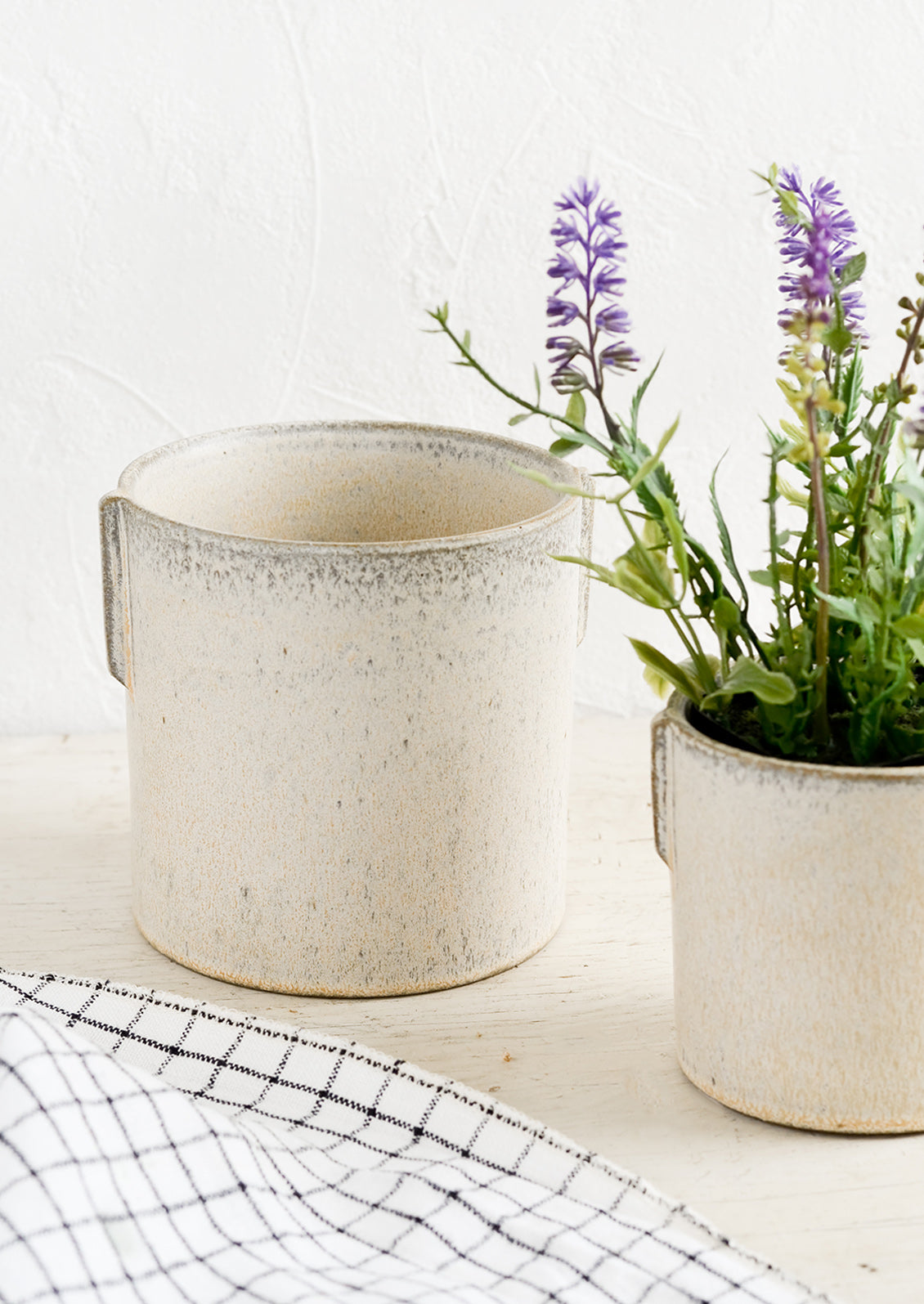 Two neutral ceramic planters in small and large sizes with lavender plant.