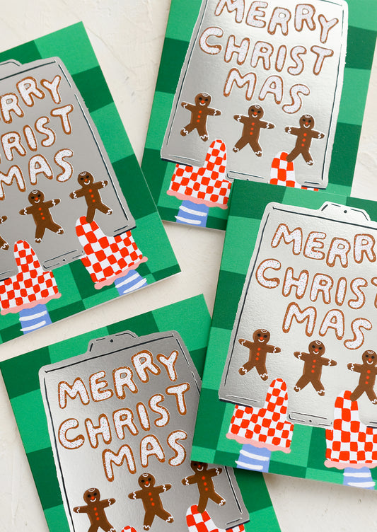 A card set with illustration of gingerbread men cookies on a tray, text reads "Merry Christmas".
