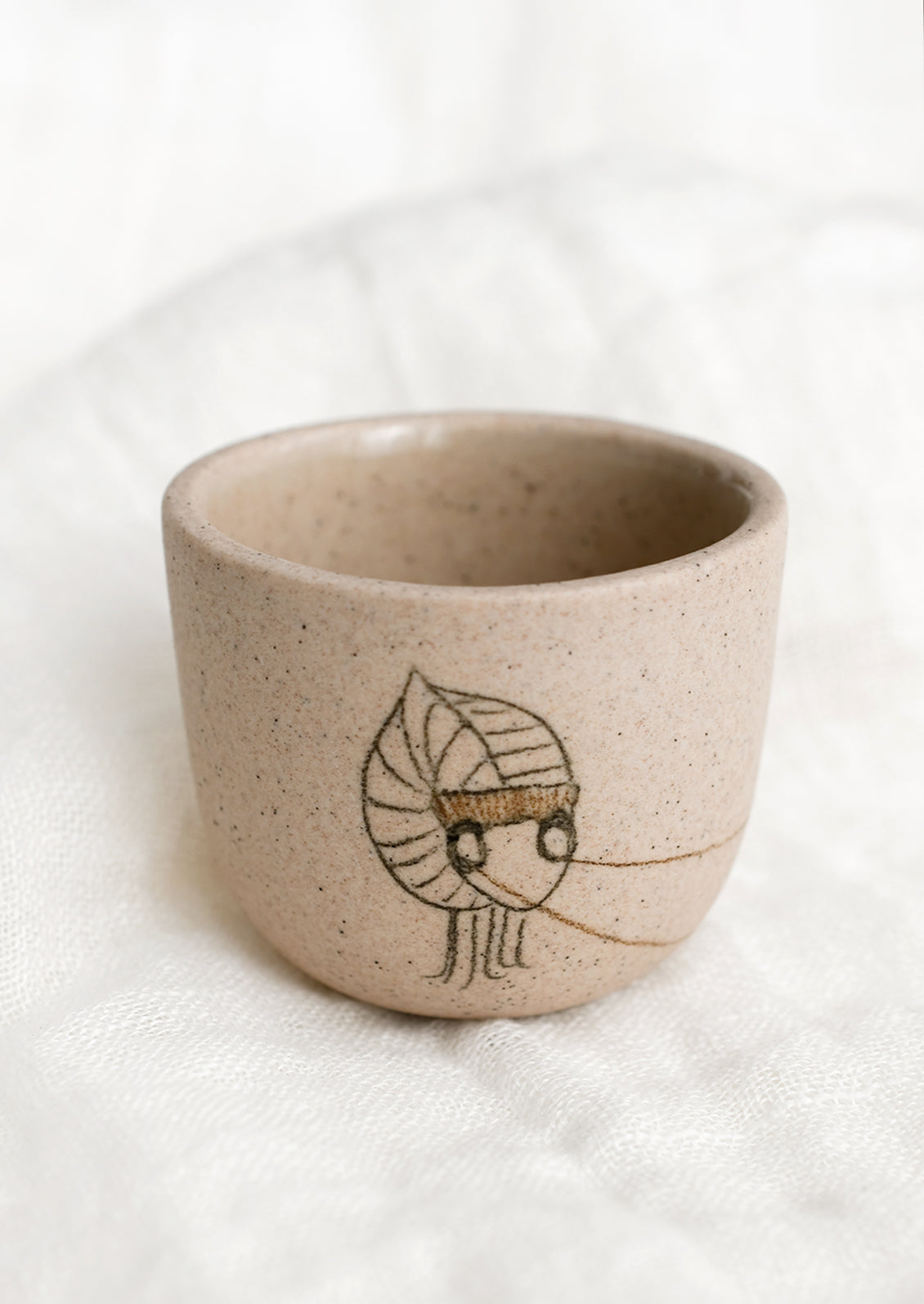 An extra small sand colored porcelain cup with katydid sketch.