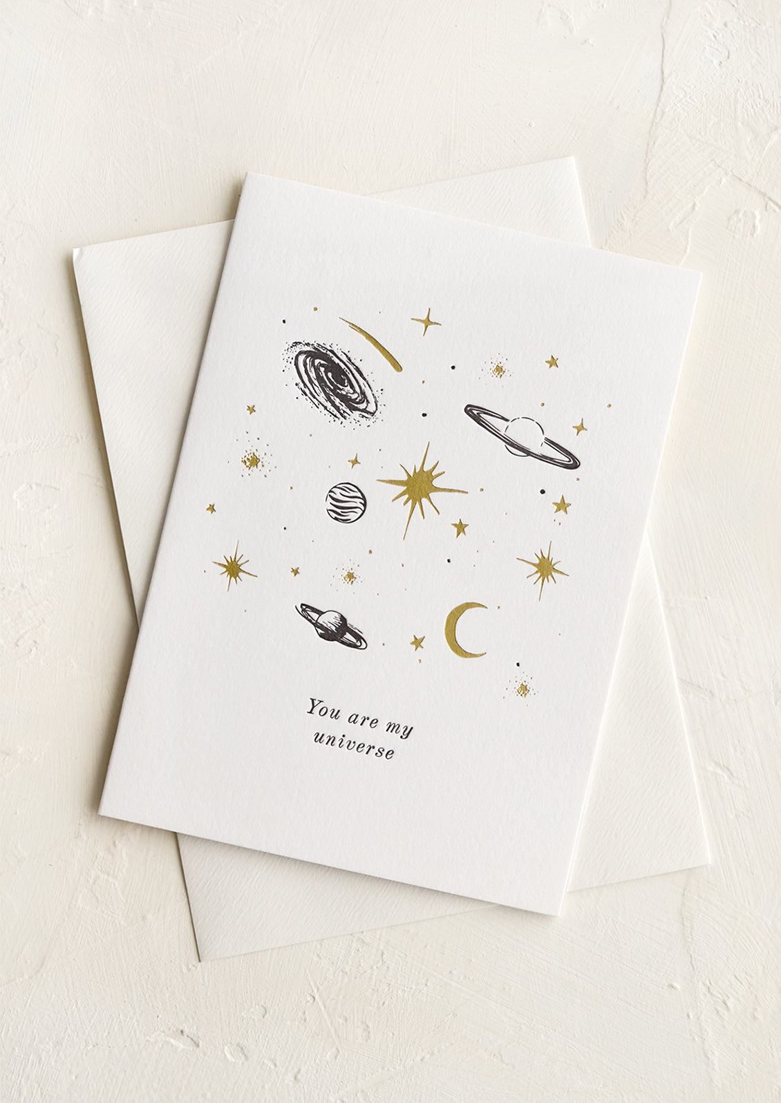A greeting card with black and gold planets and text reading "You are my universe".