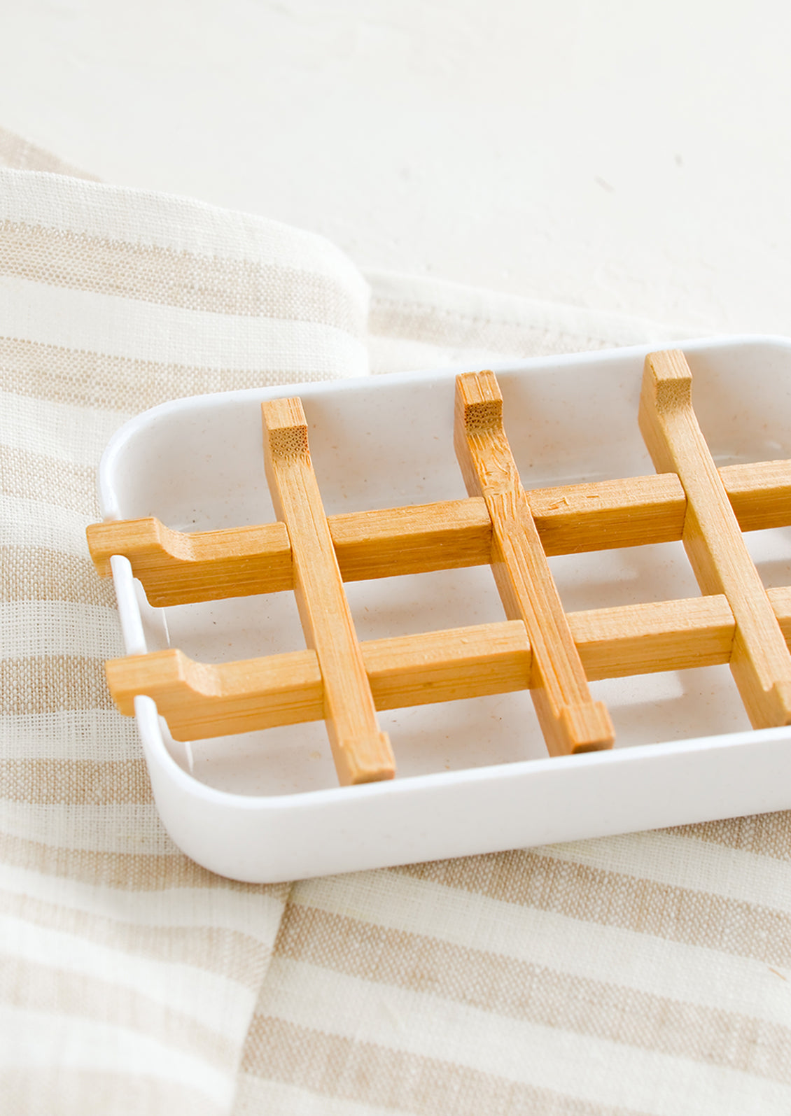 A white soap dish with built-in bamboo drainage tray.